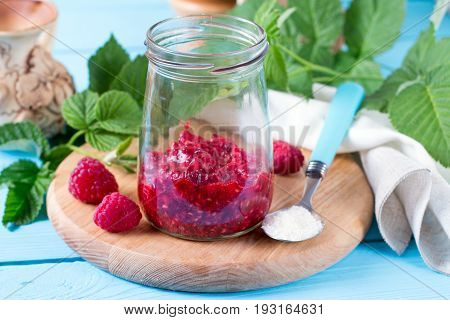 Fresh raspberries in a jar on a wooden background