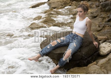 Teenage Girl Sitting On The Rocks.