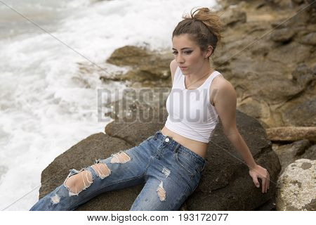 Teenage Girl Sitting On The Rocks.
