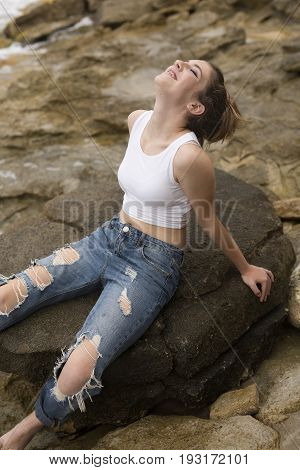 Teenage Girl Sitting On The Rocks.