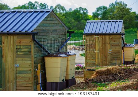 Green Recovery Of Rainwater Outside In Town Garden With Small Wooden Cabin