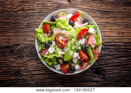 Salad. Fresh summer lettuce salad.Healthy mediterranean salad olives tomatoes parmesan cheese and prosciutto.