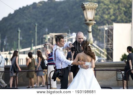 BUDAPEST, HUNGARY. 23 JUNE, 2017: A group of wedding photographers on the streets of Budapest is holding a photo session for a couple of newlyweds.