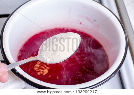 Strawberry jam making on a wooden background