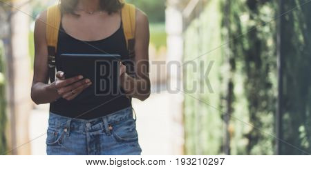 Hipster young girl with bright backpack and vintage camera using tablet or holding gadget planning travel plan. View tourist traveler on background Parc Laberint Barcelona. Mock up for text message
