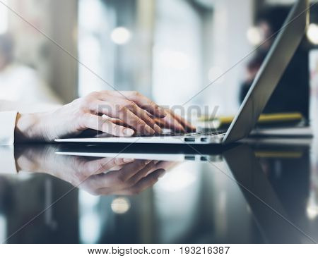 Young woman writing text hands on the open laptop in a cafe on a table with reflection and glare businesswoman working on computer