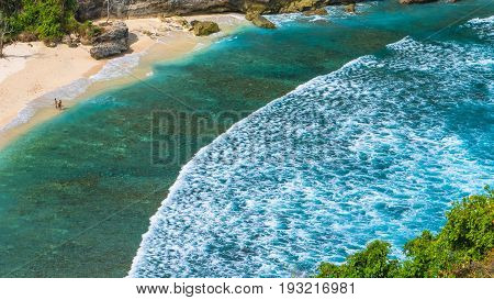 Couple on beautiful Atuh Beach with White Long Waves, Nusa Penida, Bali, Indonesia.