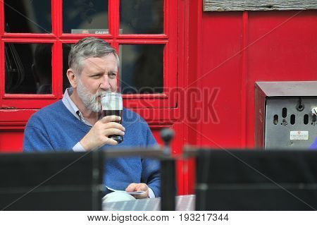 Galway City Center, Ireland June 2017,man Drinking A Pint Of Guiness In A Bar Terrace