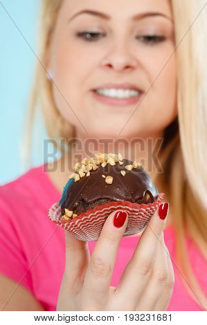 Diet sweets food concept. Woman holding delicious chocolate cupcake with peanut frosting about to take bite