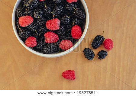 Summer berries in a pialat on wooden background close-up