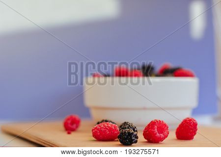 Summer berries in a pialat on wooden background close-up