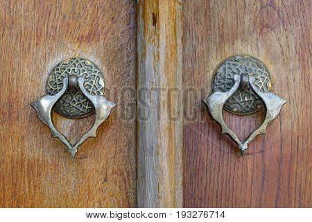 Closeup of two antique copper ornate door knockers over an aged wooden ornate door Fatih Mosque Istanbul Turkey