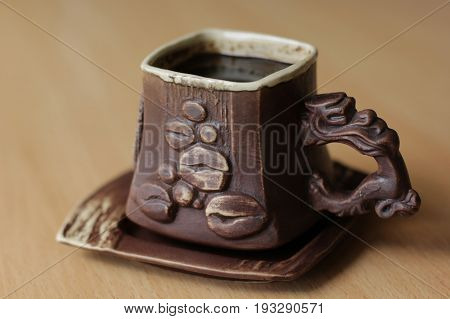 The cup of coffee with a saucer on the table