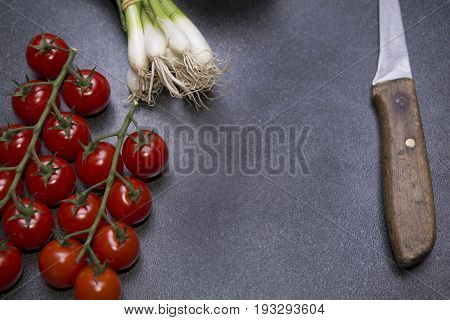 Tomato and young onions on the table with knife