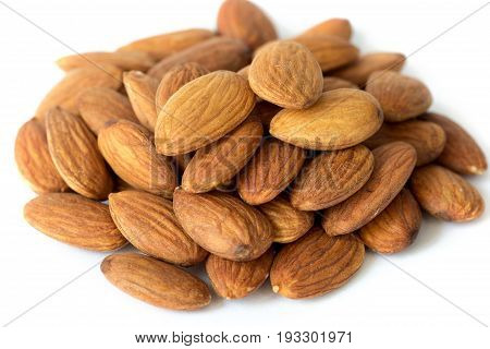 Heap of brown apricot kernels on white background close up