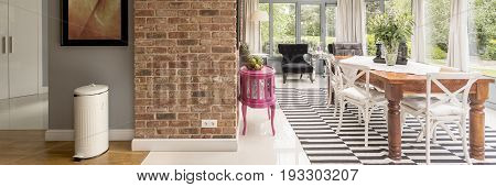 Stylish scandinavian dining area with wooden table chairs patterned flooring in orangery