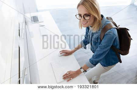   Beautiful lady smiling while testing all the technological capabilities of a mockup personal computer at an electronics section of a department store.