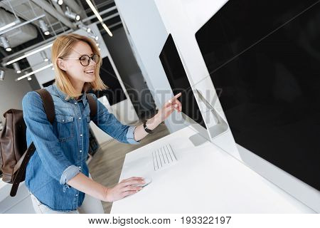  Radiant female shopper smiling and working with a mockup computer while shopping at an electronics section of a department store.