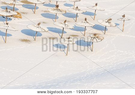 Winter on the beach. Snow on the sand and parasol. Sunshades covered by snow and ice. Novi Sad, Serbia
