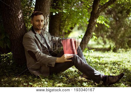 middle aged man rading book in park