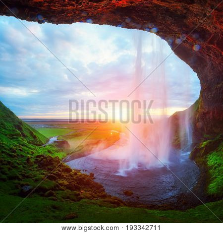 Sunrise on Seljalandfoss waterfall on Seljalandsa river, Iceland, Europe. Amazing view from inside