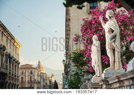 Statue outside the Church of St. Agatha in Catania Sicily with the town and Mount Etna in the background