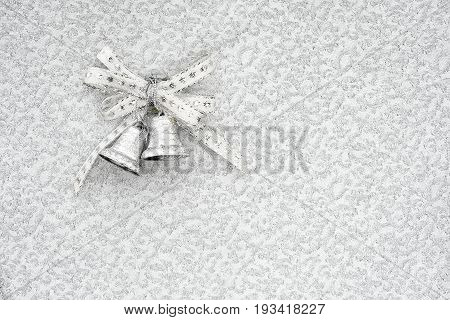 silver jingle bells on a silver background with copy space. conceptual christmas background.