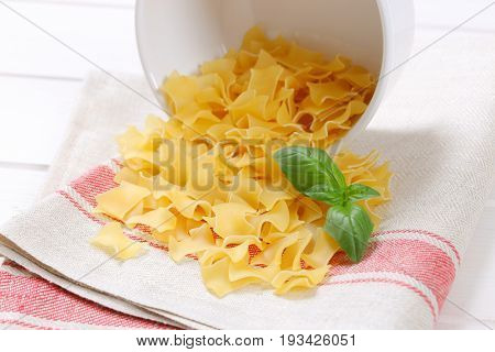 bowl of quadretti - square shaped pasta spilt out on place mat - close up