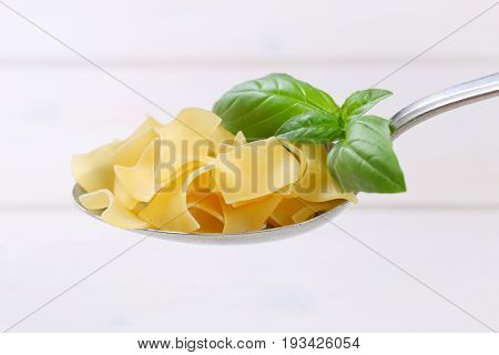 spoon of quadretti - square shaped pasta on white wooden background