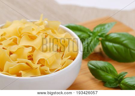 bowl of quadretti - square shaped pasta on wooden cutting board - close up
