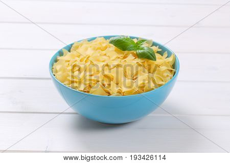 bowl of quadretti - square shaped pasta on white wooden background
