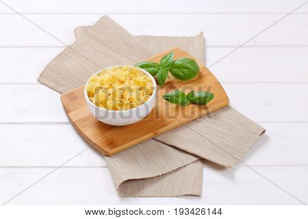 bowl of quadretti - square shaped pasta on wooden cutting board