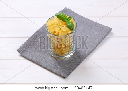 glass of quadretti - square shaped pasta on grey place mat