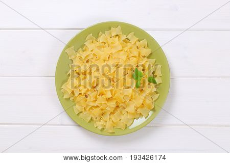 plate of quadretti - square shaped pasta on white wooden background