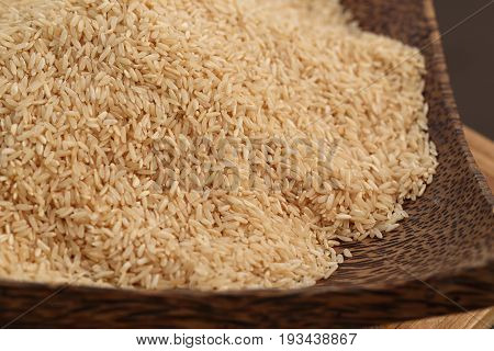 Coarse rice or half polished rice background uncooked raw cereals in bamboo wicker basket shallow depth of field.