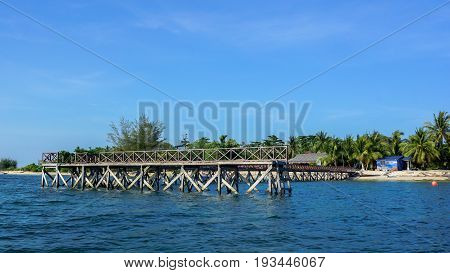 Wooden jetty over the beautiful Rusukan Besar island tropical beach with blue sky and clouds in Labuan Pearl of Borneo,Sabah.