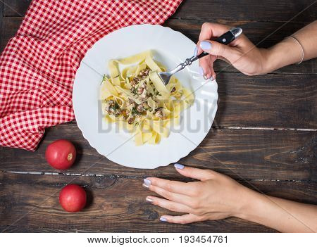 Top View of Woman Eating pasta with Mushrooms on wood table.