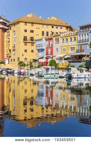 VALENCIA, SPAIN - JUNE 13, 2017: Colorful houses reflected in the water of Port Saplaya in Valencia, Spain