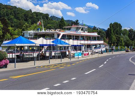 Thun, Switzerland - 21 July, 2015: road and pier in the city of Thun, mountains in the background. Thun is a city and municipality in the administrative district of Thun in the Swiss canton of Bern, located where the Aare river flows out of Lake Thun