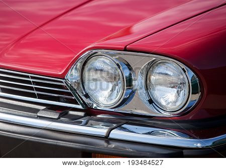Headlights red vintage car close up on a city street
