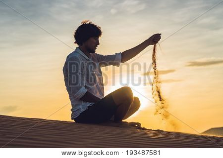 A Man Is Pouring Sand In The Desert. Sand Through The Fingers Of The Concept