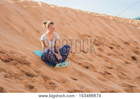 Young Woman Rolls On A Toboggan In The Sledge In The Desert