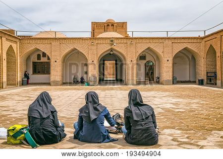 YAZD, IRAN - MAY 5, 2015: Three women sitting in the yard of the Yame mosque in old city.