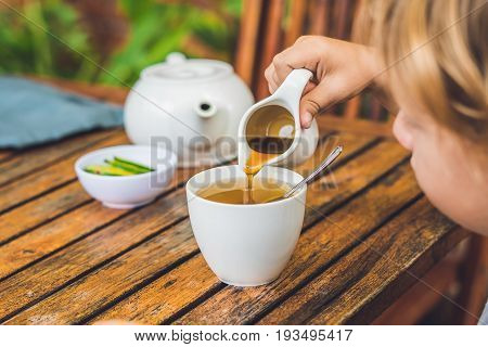 Happy Nice Boy Pours Honey Into The Tea In Summer Green Garden. Portrait. Outdoor