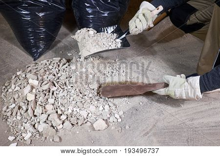 Worker cleaning rubble with brush and dustpan