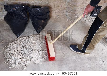 Worker sweeping the rubble with red broom