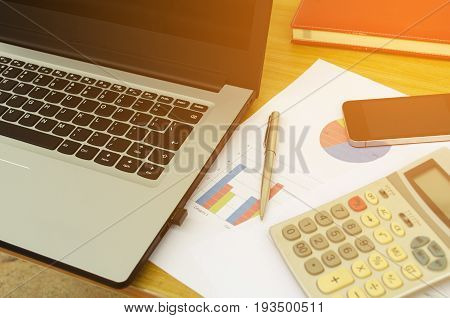 close up business accessories laptop calculator datasheet pen notebook and smartphone on desk financial report saving and economy business concept sunlight effect soft focus selective focus