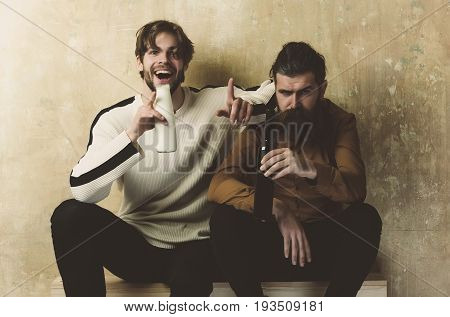 Health Happy man in sweater laughing with yogurt or milk bottle. Serious model with beard in shirt sitting with wine. Friends friendship convive. bad habits and addictive
