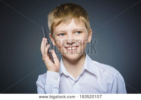 Closeup Portrait of happy boy with mobile or cell phone on gray background.