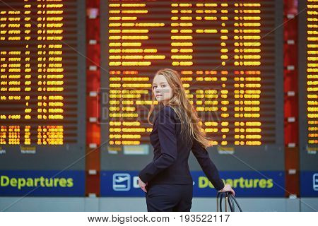 Woman With Hand Luggage In International Airport Terminal, Looking At Information Board